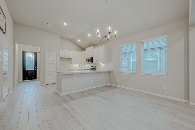 kitchen featuring kitchen peninsula, appliances with stainless steel finishes, a chandelier, white cabinetry, and hanging light fixtures