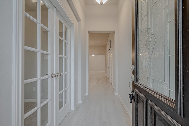 corridor featuring light wood-type flooring and french doors