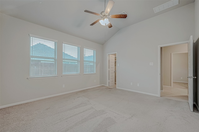 unfurnished bedroom with a walk in closet, ceiling fan, light carpet, and lofted ceiling