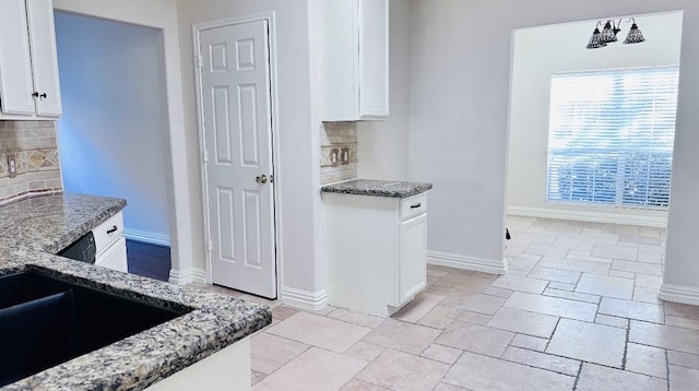 kitchen with tasteful backsplash, white cabinetry, and dark stone countertops