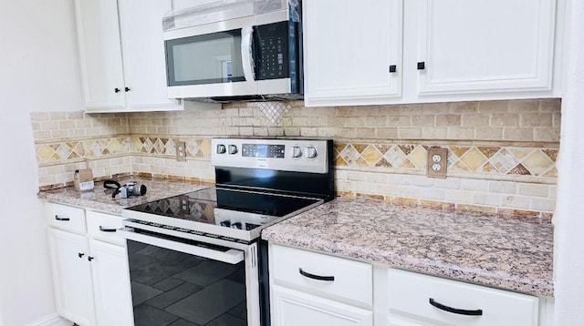 kitchen featuring tasteful backsplash, white cabinetry, light stone counters, and appliances with stainless steel finishes