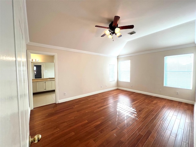 empty room featuring ornamental molding, vaulted ceiling, ceiling fan, and dark wood-type flooring