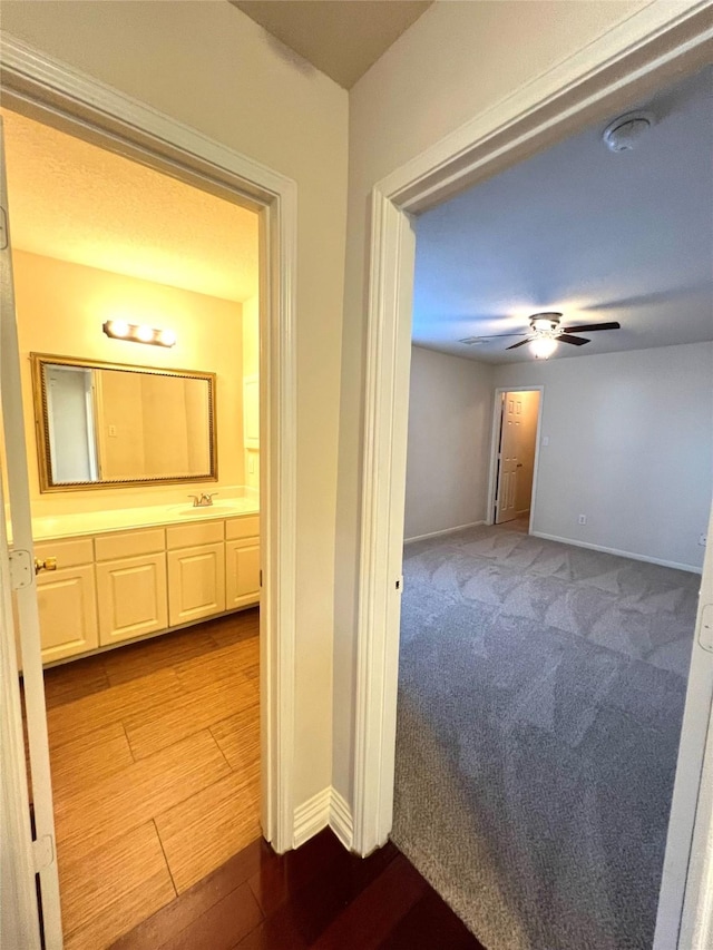 corridor featuring sink and light carpet