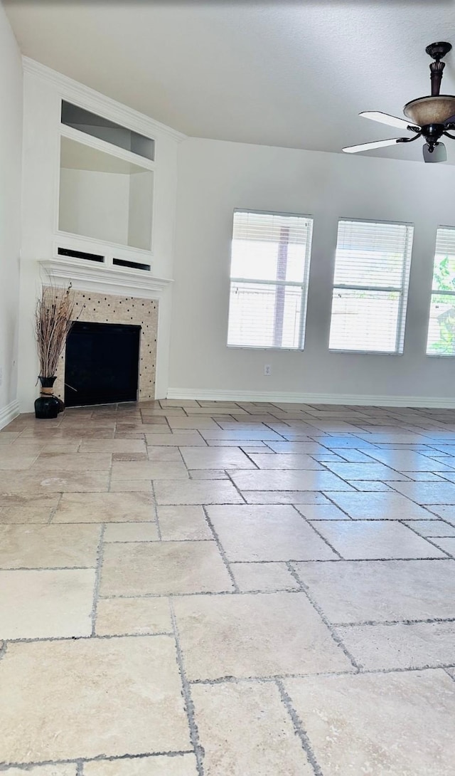 unfurnished living room with ceiling fan and a tiled fireplace