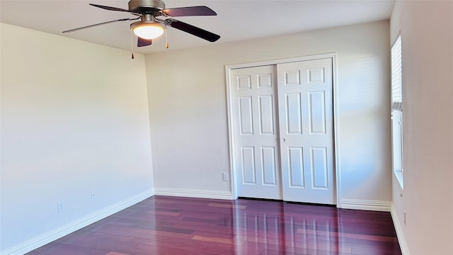 unfurnished bedroom with ceiling fan, dark wood-type flooring, and a closet