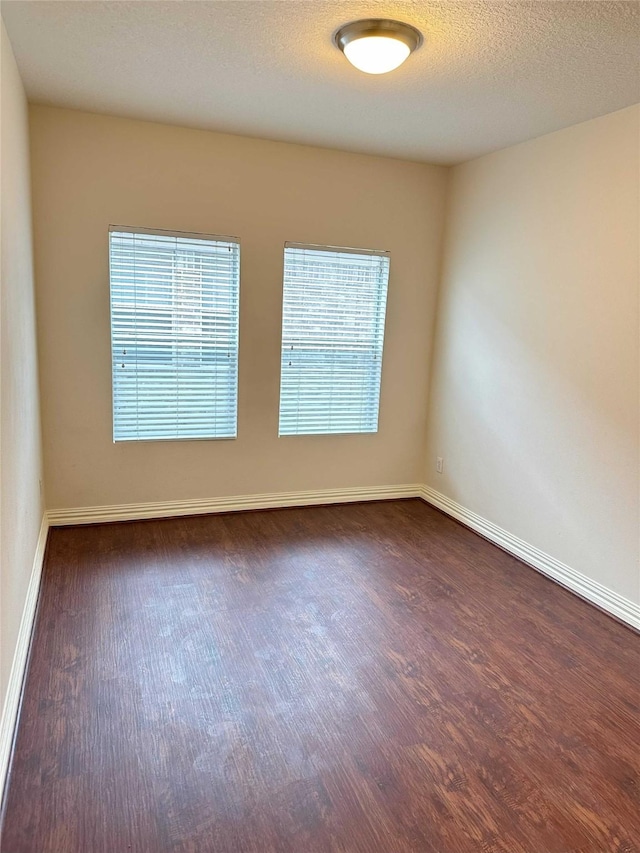 unfurnished room featuring a textured ceiling and dark wood-type flooring