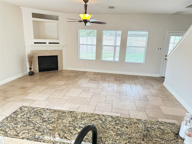 unfurnished living room with ceiling fan and a fireplace