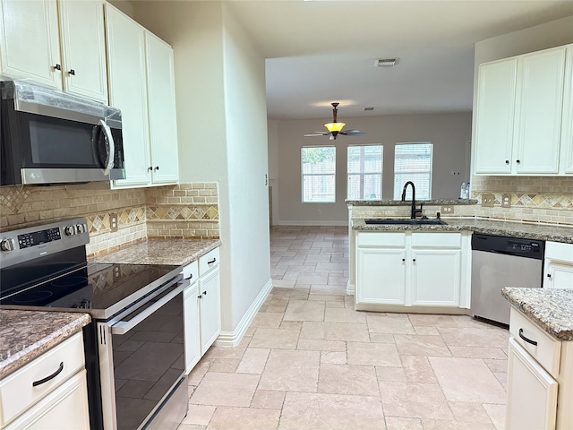 kitchen featuring appliances with stainless steel finishes, light stone counters, ceiling fan, sink, and white cabinetry