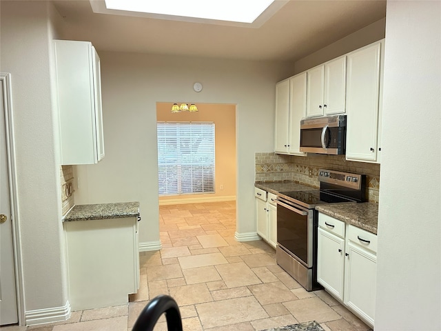 kitchen with white cabinets, backsplash, dark stone countertops, and stainless steel appliances