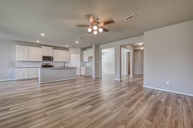 unfurnished living room with ceiling fan, sink, light hardwood / wood-style floors, and a textured ceiling