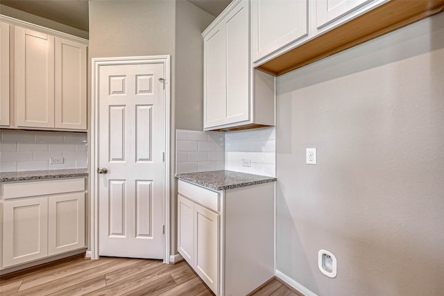 kitchen featuring decorative backsplash, light hardwood / wood-style floors, white cabinetry, and dark stone countertops