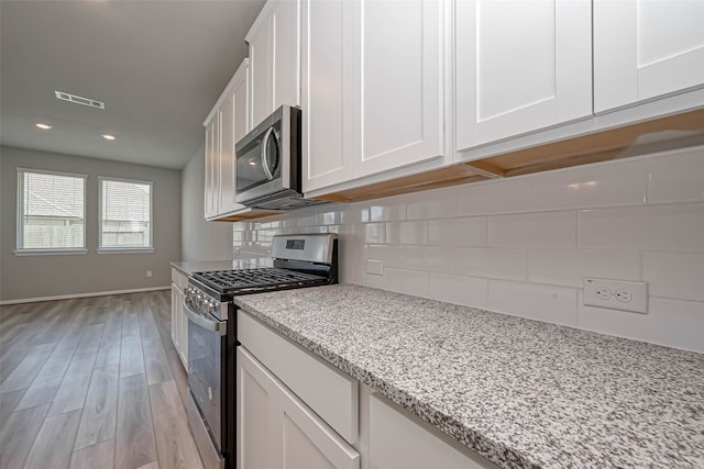 kitchen featuring light stone countertops, stainless steel appliances, light hardwood / wood-style flooring, and white cabinetry