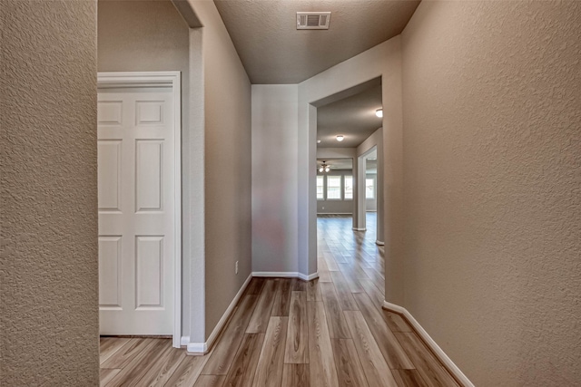 corridor featuring light hardwood / wood-style floors and a textured ceiling