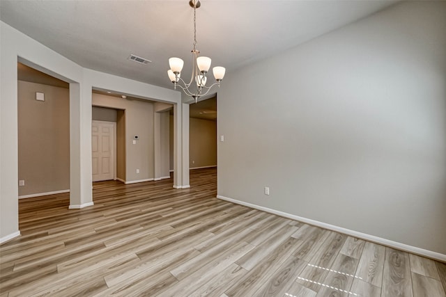 spare room featuring light hardwood / wood-style floors and an inviting chandelier