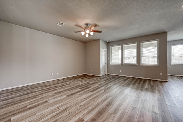 spare room with ceiling fan, a textured ceiling, and light wood-type flooring