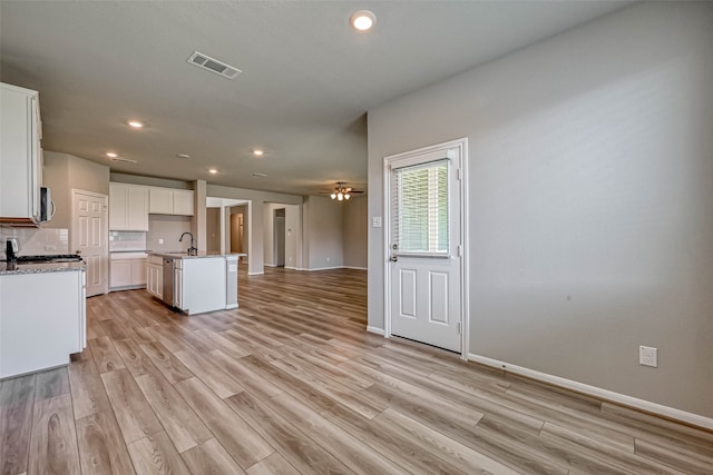 kitchen with a center island with sink, white cabinets, and light hardwood / wood-style flooring