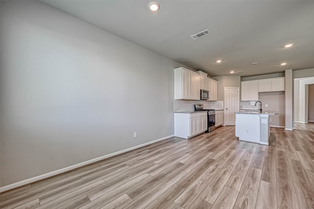 kitchen featuring a center island with sink, white cabinets, light wood-type flooring, and appliances with stainless steel finishes