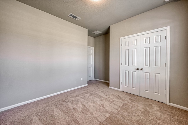 unfurnished bedroom with light carpet, a textured ceiling, and a closet