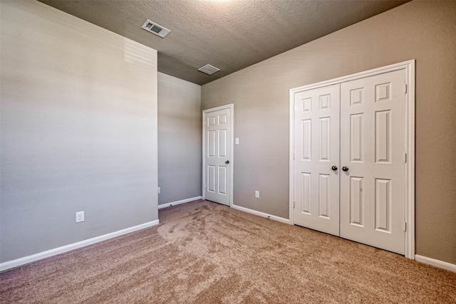 unfurnished bedroom with carpet flooring, lofted ceiling, a textured ceiling, and a closet