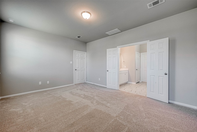 unfurnished bedroom featuring light colored carpet and ensuite bath