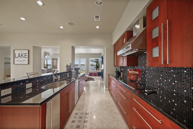 kitchen featuring black electric stovetop, tasteful backsplash, wall chimney exhaust hood, sink, and dark stone countertops