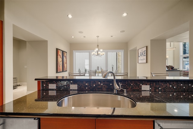 kitchen with dark stone countertops, sink, decorative light fixtures, and a notable chandelier