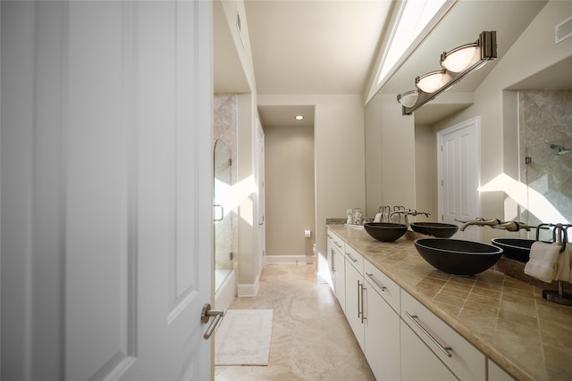 bathroom featuring a shower with door and vanity