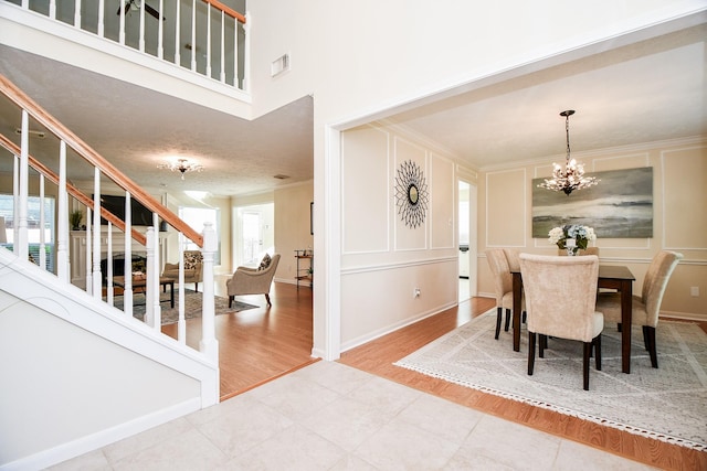 dining space with a chandelier, a high ceiling, hardwood / wood-style flooring, and ornamental molding