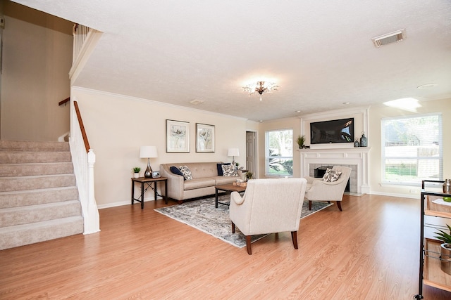 living room featuring light hardwood / wood-style floors, a textured ceiling, and ornamental molding