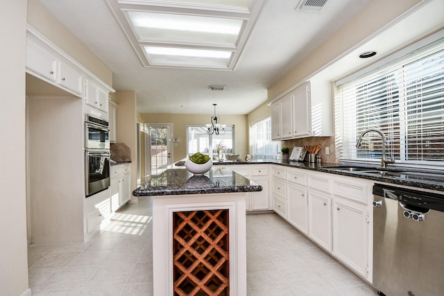 kitchen featuring appliances with stainless steel finishes, sink, pendant lighting, white cabinets, and a kitchen island