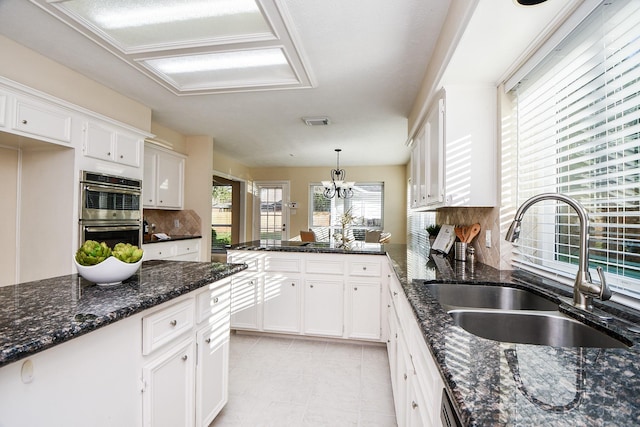 kitchen with sink, hanging light fixtures, double oven, a notable chandelier, and white cabinetry