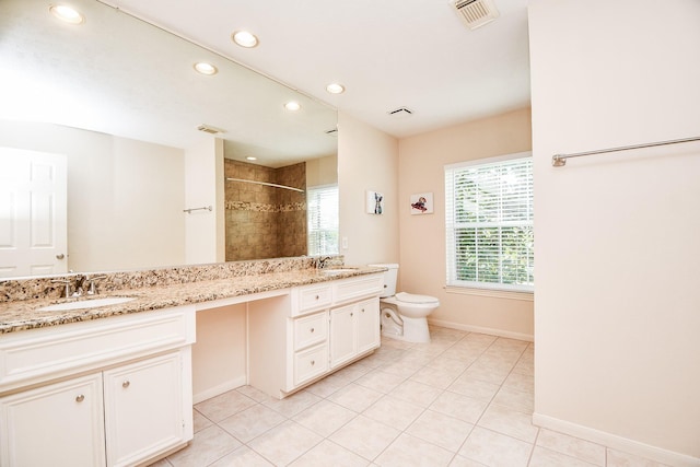 bathroom featuring toilet, tile patterned flooring, vanity, and tiled shower