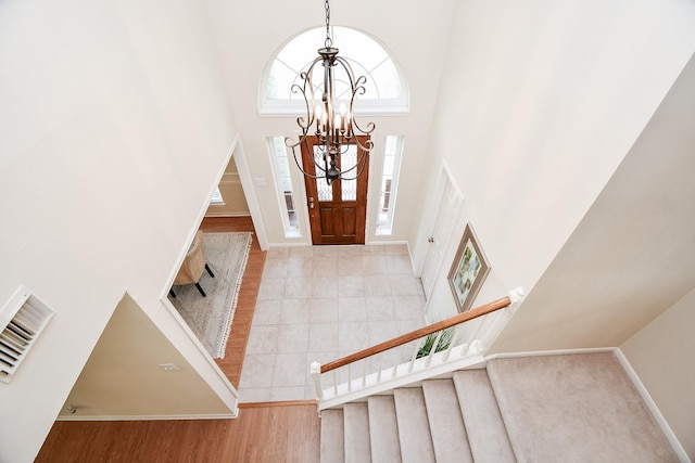 foyer entrance with a notable chandelier, light hardwood / wood-style floors, and a high ceiling