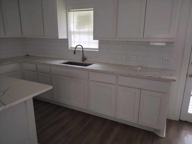 kitchen with white cabinets, dark hardwood / wood-style floors, light stone countertops, and sink