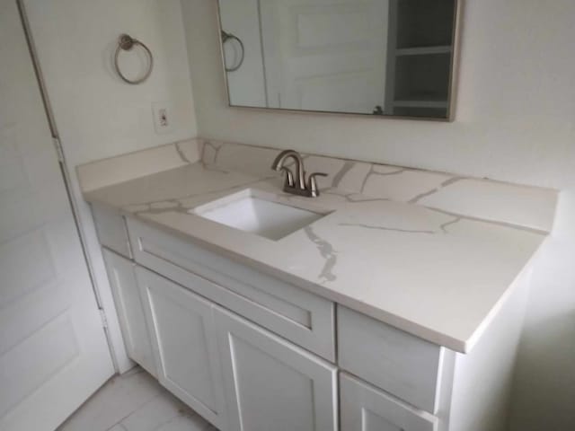 kitchen with white cabinets, light stone counters, and sink