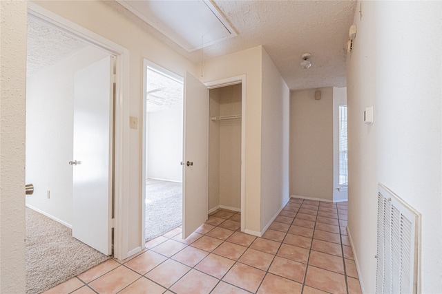 corridor with a textured ceiling and light colored carpet