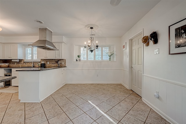 kitchen with white cabinets, decorative light fixtures, backsplash, and range hood