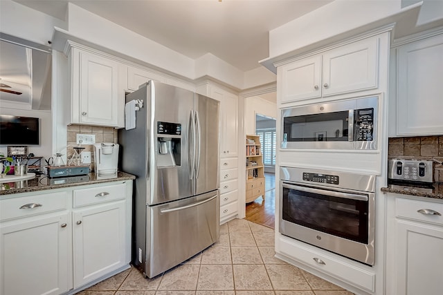 kitchen with appliances with stainless steel finishes, white cabinetry, and dark stone counters