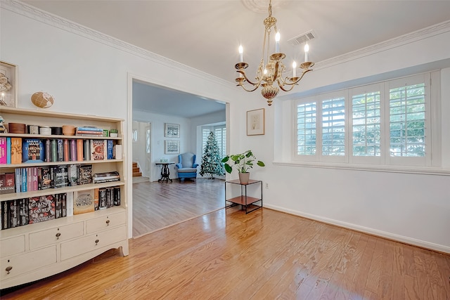 sitting room featuring crown molding, wood-type flooring, and a notable chandelier