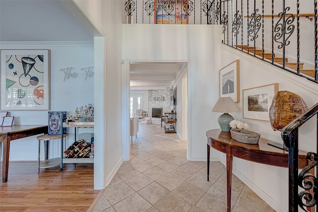 foyer entrance with a fireplace, light hardwood / wood-style floors, and crown molding