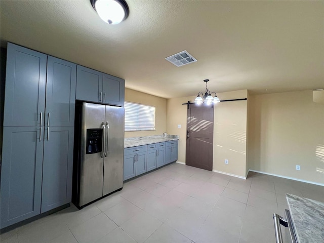 kitchen with light stone countertops, stainless steel fridge, pendant lighting, a chandelier, and a textured ceiling