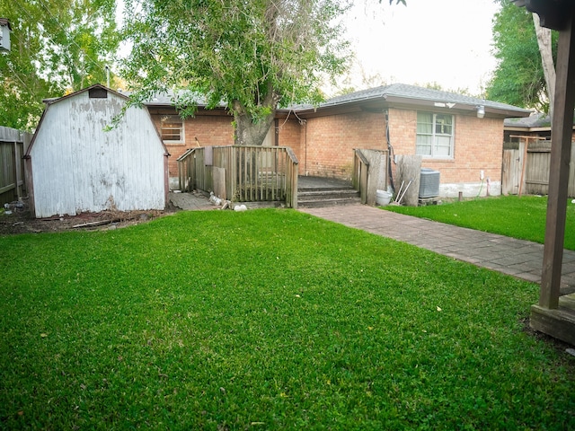 rear view of house with central AC, a yard, and a storage unit