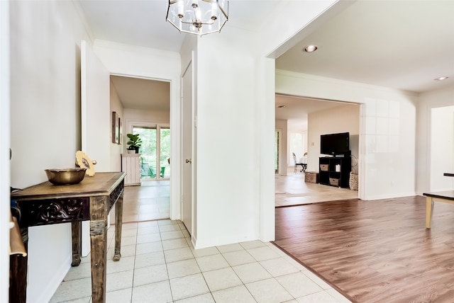 foyer entrance with a chandelier, ornamental molding, and light hardwood / wood-style flooring