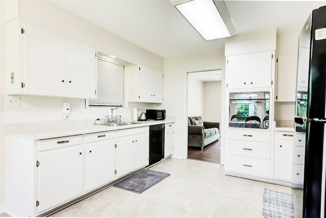 kitchen with sink, white cabinets, black appliances, and light wood-type flooring