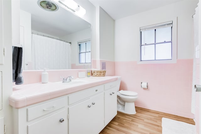 bathroom with vanity, wood-type flooring, tile walls, and toilet