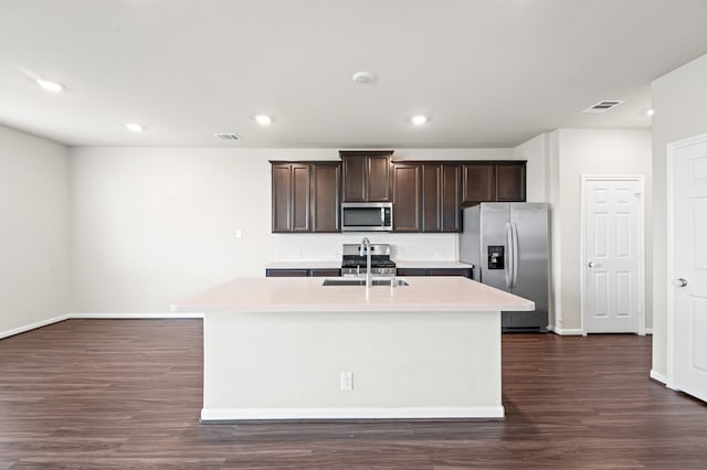 kitchen with dark brown cabinets, stainless steel appliances, sink, dark hardwood / wood-style floors, and an island with sink