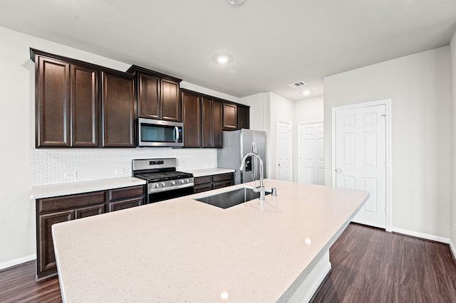 kitchen featuring dark hardwood / wood-style flooring, stainless steel appliances, a kitchen island with sink, and sink