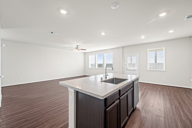 kitchen with ceiling fan, sink, dark wood-type flooring, an island with sink, and dark brown cabinets