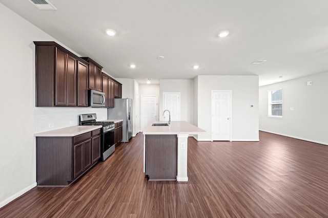 kitchen featuring dark wood-type flooring, a center island with sink, sink, dark brown cabinets, and stainless steel appliances