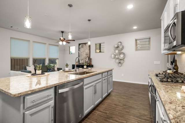 kitchen featuring ceiling fan, sink, stainless steel appliances, dark hardwood / wood-style floors, and a center island with sink